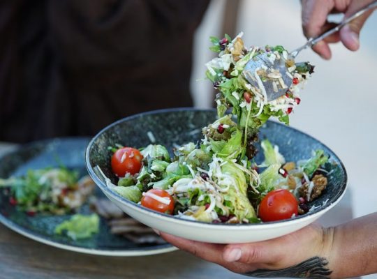 Colorful fresh garden salad with cherry tomatoes being served outdoors on a sunny day.