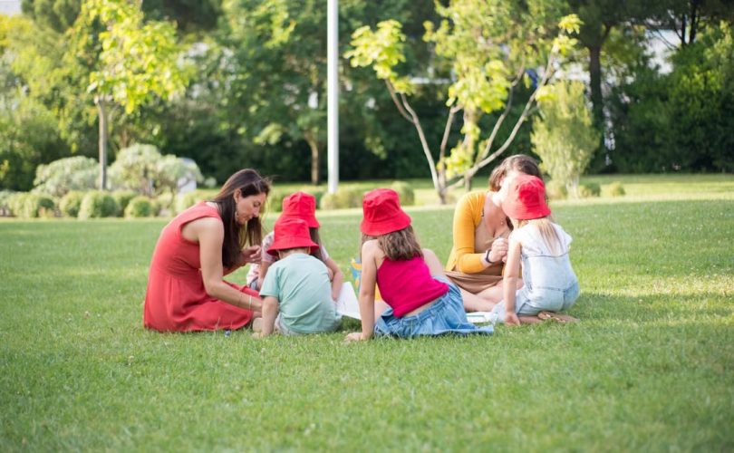 A family enjoys a summer picnic outdoors, bonding and relaxing in a sunny park setting.