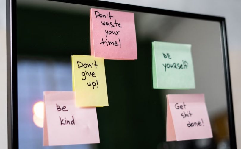 Colorful sticky notes with motivational messages on a mirror reflecting positivity.